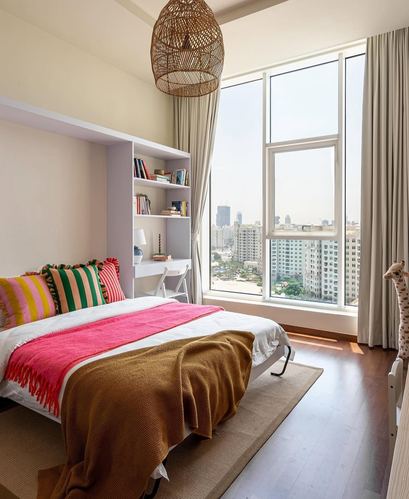 Colourful bedroom with rattan pendant, built-in shelving, and floor-to-ceiling city view window