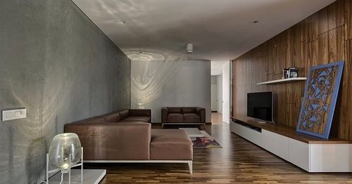 Living room with concrete wall, wood-paneled tv wall, brown leather sofas and dark wood flooring