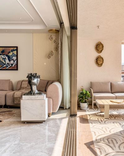 Two connected living areas divided by a fluted brass sliding partition, marble floors, sculptural decor