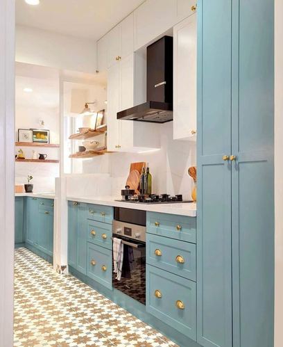 Galley kitchen with dusty blue cabinets, white countertop, black hood, patterned tile floor