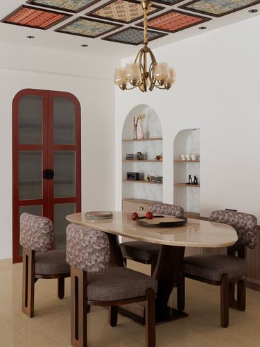 Dining room with oval marble table, patterned ceiling panels, arched shelving niches and a red glass cabinet