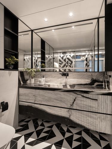 Black and white marble bathroom vanity with ribbed panelling and geometric tiled floor.