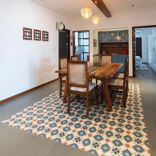 Dining area with cane-back wooden chairs on patterned tile rug, pendant lights above table