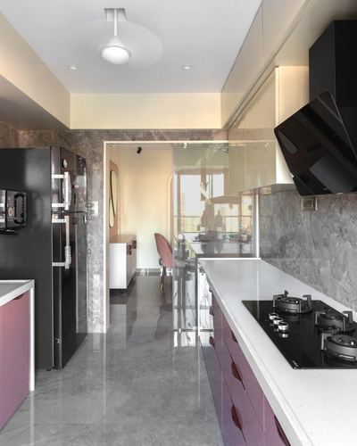 Galley kitchen with mauve cabinetry, black hob, and gray stone walls leading to dining area