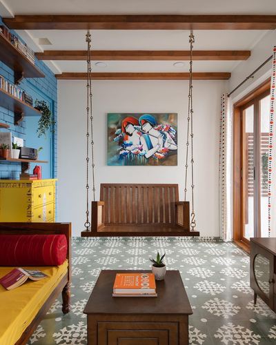 Colourful living room with a wooden swing, patterned floor tiles, yellow cabinet, and a couple's painting on the wall