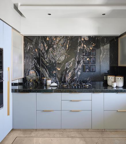 Pale blue kitchen with gold handles and a dramatic dark veined stone backsplash