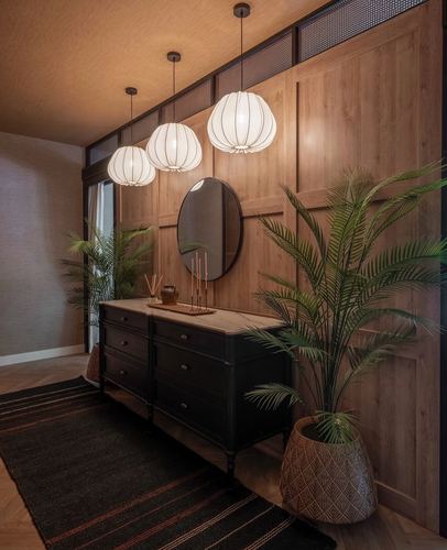 Wood-paneled hallway with three glowing lantern pendants over a black sideboard and round mirror