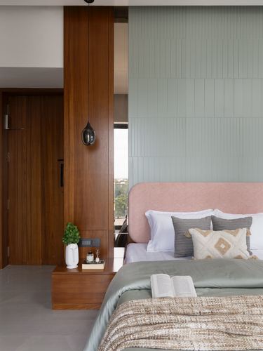 Bedroom corner with ribbed green tile wall, pink upholstered headboard, and wooden floating nightstand