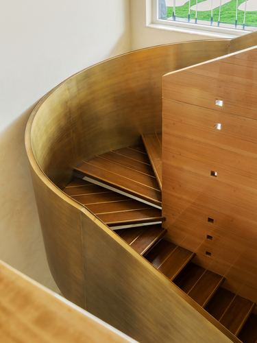 Overhead view of a spiral staircase with brass curved wall and wooden perforated screen