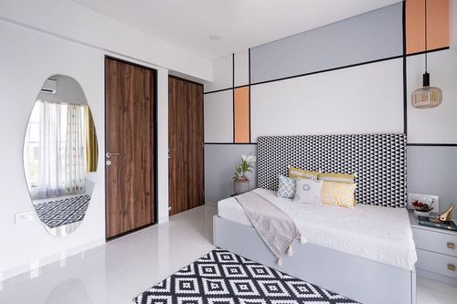 Mumbai bedroom with pastel color-blocked wall, triangle headboard, oval mirror and wooden doors