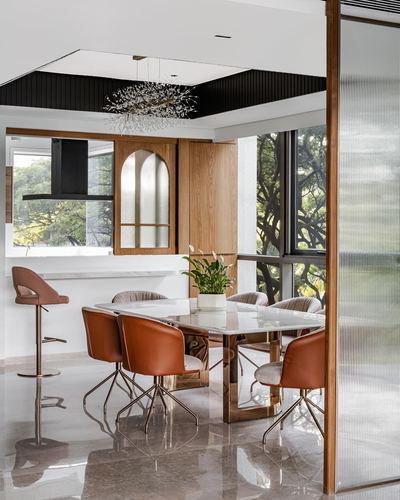 Dining area with marble table, terracotta leather chairs, brass legs, floor-to-ceiling windows and arched wood cabinet