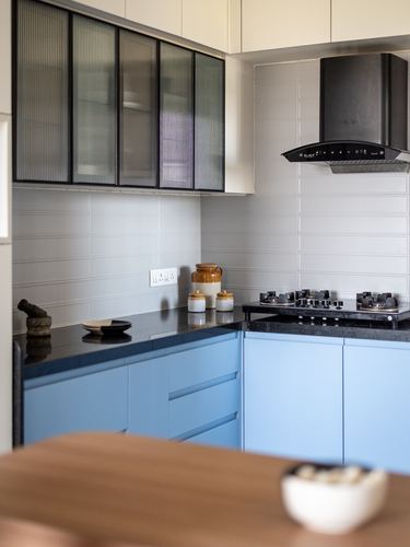 Blue and white modular kitchen corner with black countertop, hob, and chimney hood