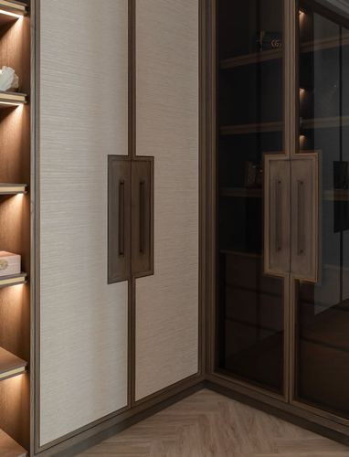 Corner of a wardrobe with textured wood-toned panels, brass handles, glass cabinet, and herringbone flooring