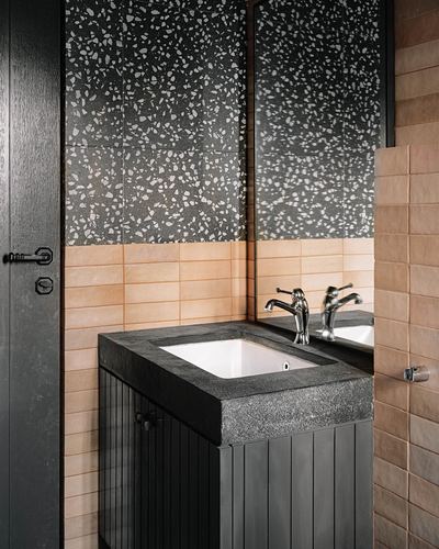 Bathroom vanity with terrazzo wall, concrete counter, and fluted black cabinetry