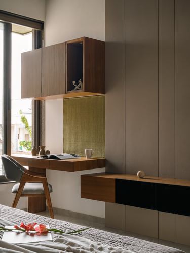 Wall-mounted wooden desk with cabinet above, olive textured backdrop, window light, Ahmedabad home