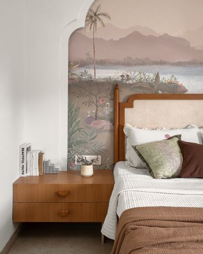 Bed with wooden headboard set in an arched niche painted with a landscape mural, floating wooden nightstand beside it
