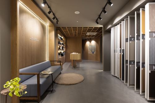 Showroom interior with wood-panelled wall, blue sofa, and rows of hanging material sample panels