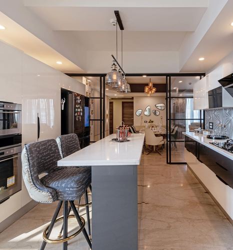 Open kitchen island with marble counter, black steel glass partitions leading to dining area beyond