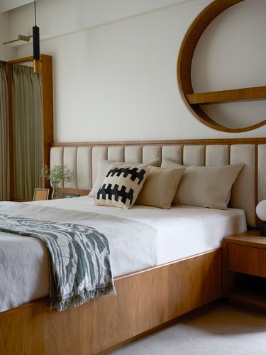 Walnut bed with channel-tufted headboard, circular wood shelf, and green printed throw