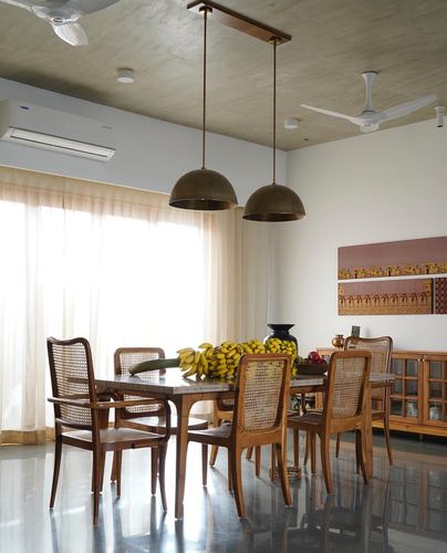 Dining room with cane chairs, stone-top table, and two brass dome pendant lights