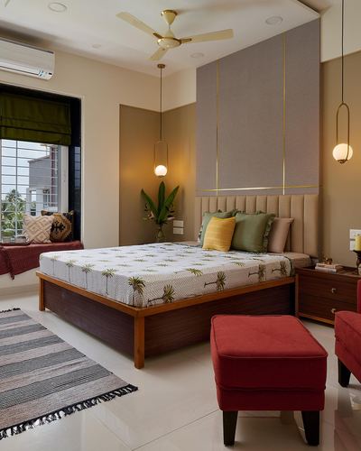 Bedroom with channel-tufted beige headboard, brass inlay lines, wooden bed, red ottoman, window seat.
