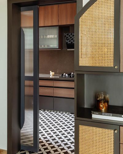 Kitchen entrance with fluted glass door, cane cabinetry, and patterned tile floor
