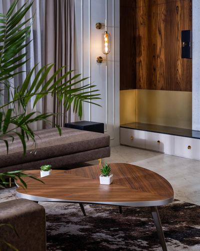 Living room corner with wood-panelled wall, brass sconce, and organic wooden coffee table on stone floor