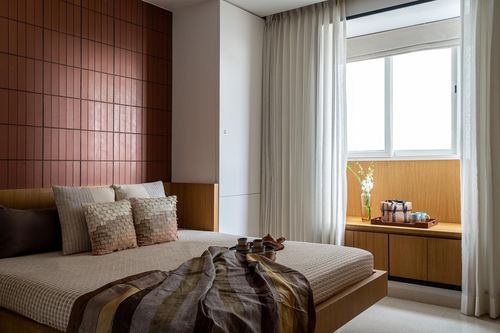 Bedroom with terracotta tiled headboard wall, wooden bed, and sunlit window seat