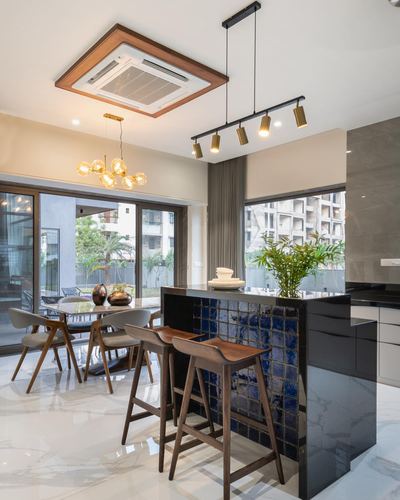 Open kitchen island with blue glazed tile facing, wooden bar stools, dining area beyond glass doors