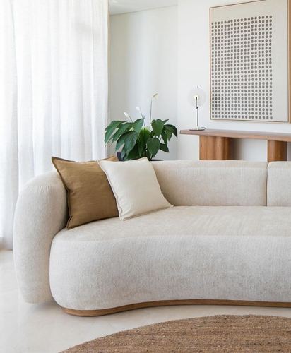 Curved boucle sofa with olive and cream pillows beside a console table and dotted artwork