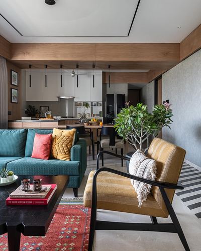 Living room with teal sofa, mustard armchair, and open kitchen beyond, warm wood tones throughout