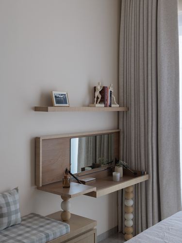 Wall-mounted wooden desk with fold-down mirror beneath a floating shelf, beside curtained window