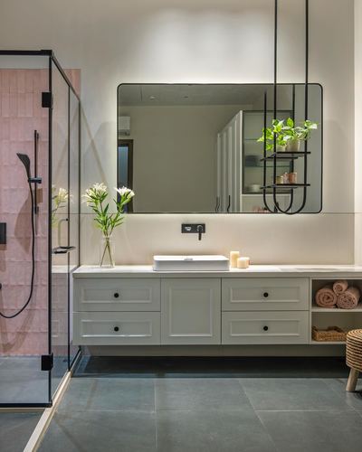 Modern bathroom vanity with backlit mirror, white cabinetry, and pink-tiled shower alcove