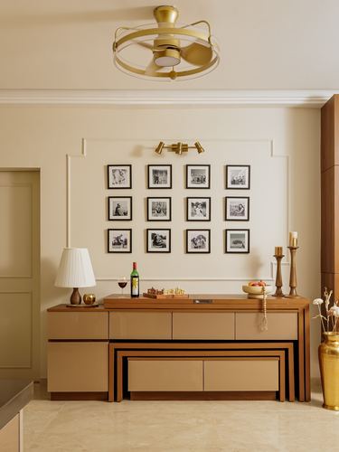 Beige dining wall with gallery of black-and-white photos above a wood sideboard and nested bench