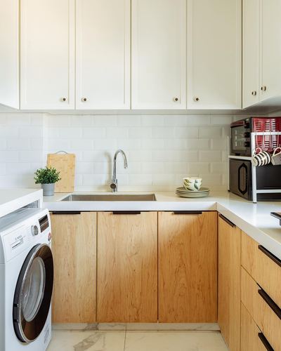 White kitchen corner with wood base cabinets, subway tile backsplash, sink, front-load washer and small appliances