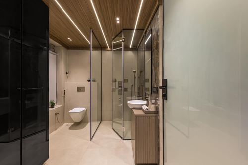 Modern bathroom with glass shower enclosures, wood-slat ceiling with LED strips, and fluted wood vanity