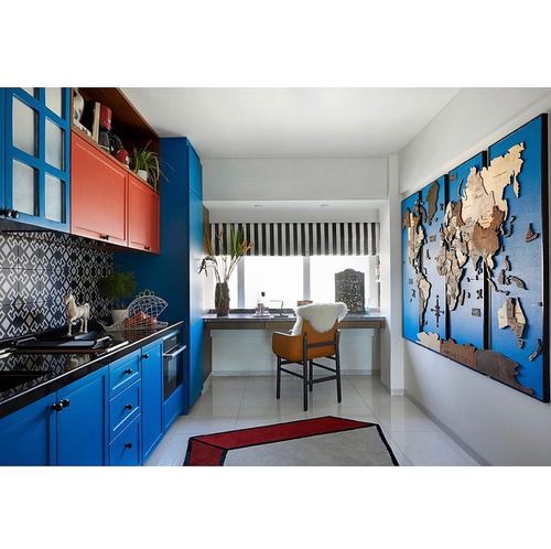 Blue-cabineted eclectic kitchen with orange upper cabinets and a wooden world map wall art