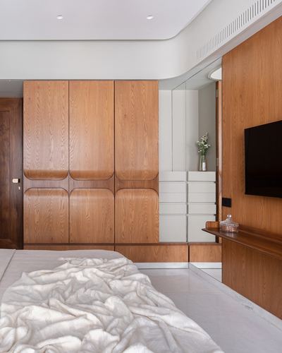 Bedroom with arched wooden wardrobe, mirrored niche, tv console and white bedding
