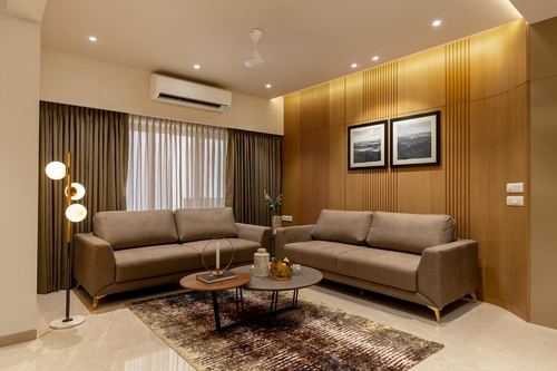 Living room with two beige sofas facing fluted wood wall and framed photos