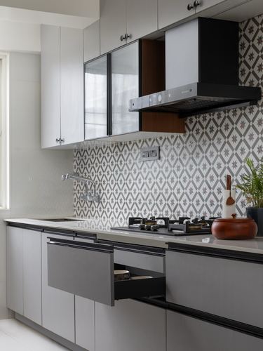 Grey modular kitchen with patterned tile backsplash, black chimney hood, and open drawer