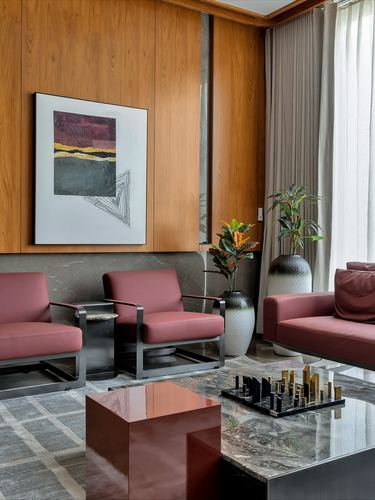 Living room with rose leather armchairs, wood panelling, and layered marble coffee tables