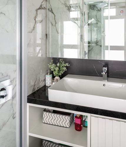 Bathroom vanity with white vessel sink, black stone counter, marble walls and mirrored cabinet
