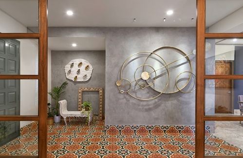 Foyer with patterned tile floor, wooden glass doors, and circular brass wall art on plaster wall