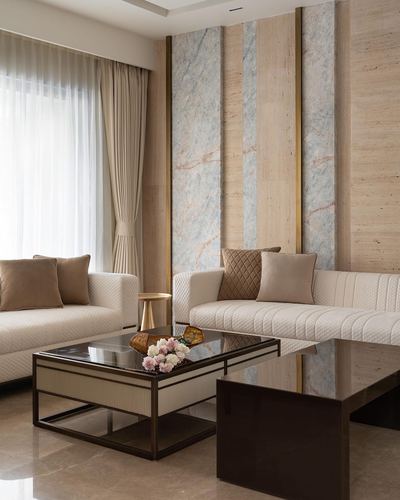 Cream sofas with quilted texture face marble-and-wood paneled wall accented in brass