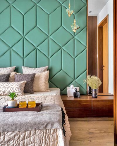 Bedroom with green geometric upholstered headboard wall and wooden console beside doorway