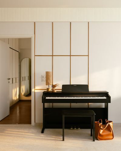 Black digital piano against a white wall with brass linear paneling and afternoon light