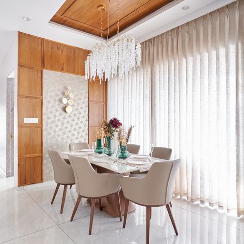 Dining room with marble table, beige upholstered chairs, crystal chandelier, and floor-to-ceiling sheer curtains
