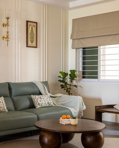 Sage green leather sofa with round wooden coffee table beside a fluted-panel wall