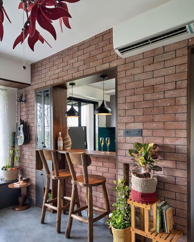 Exposed brick wall with wooden bar stools and pass-through window to kitchen with pendant lights