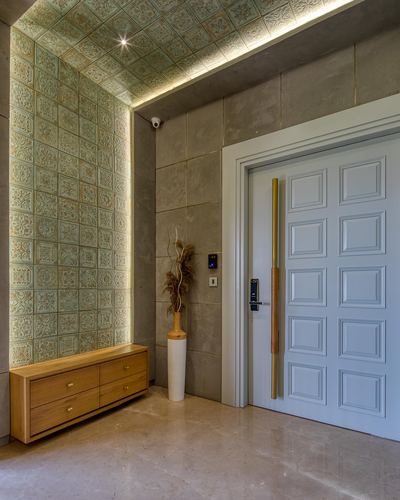 Entry foyer with patterned green tile wall curving to ceiling, wooden console, and pale blue panelled door